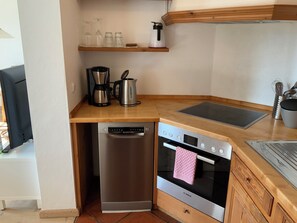 A compact kitchen with a Bosch dishwasher, an oven, a coffee maker, and a kettle on the countertop. - Beautiful, calm 2-room-apartment with big terrace and nice view (Bayern)