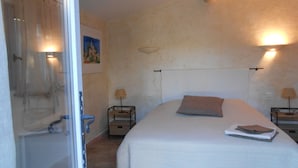 Ein Schlafzimmer mit einem Bett, zwei Nachttischen mit Lampen, einem Bild an der Wand und einer Duschkabine.