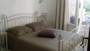 A single bed with a metal frame, a bedside table, and a window with curtains. - guest rooms 4 persons near the sea & Sainte Victoire (Trets)