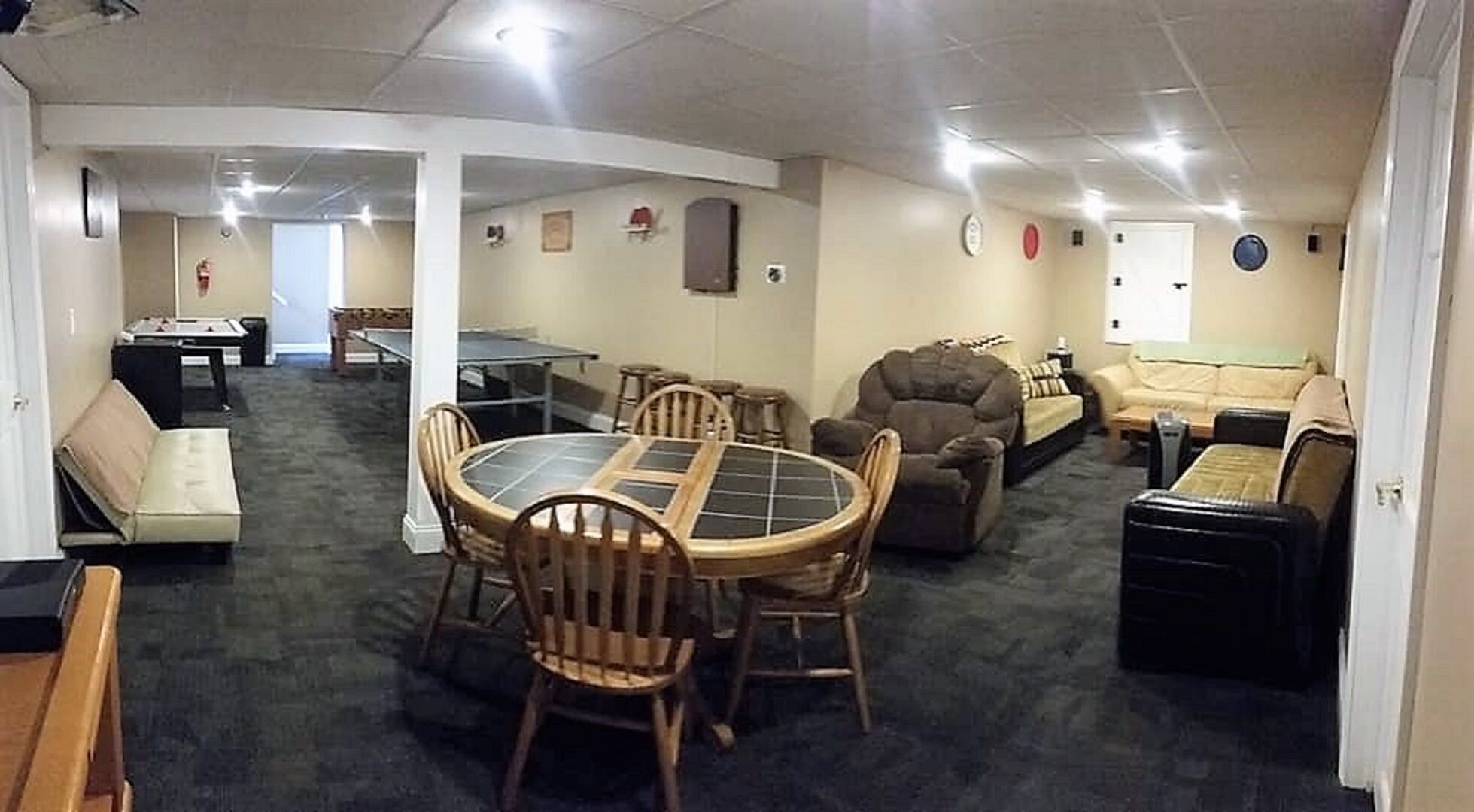 A spacious living area with a round dining table, multiple sofas, and a pool table.
