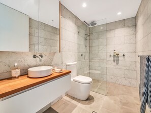 Ein modernes Badezimmer mit Marmorwaschtisch, Toilette und einer Duschkabine.