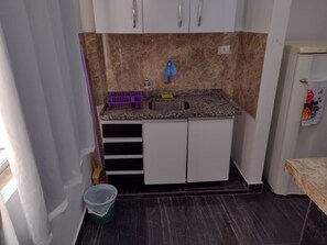 Eine kleine Küche mit einer Arbeitsplatte aus Granit, einem Spülbecken und einem Hängeschrank.