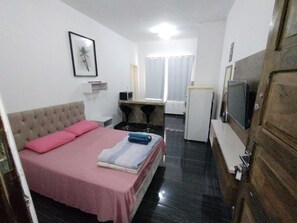 Ett hotellrum med en säng, ett skrivbord, en tv och en garderob.