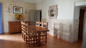 A dining area with a wooden table and chairs, a vase of sunflowers, and a stone wall. - Authentic village house of 150 m² with swimming pool close to the city center (Sablet)