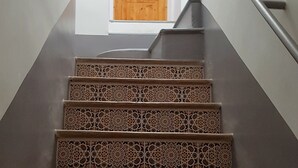 Eine Treppe mit aufwendigen Fliesenmustern führt zu einer Holztür.