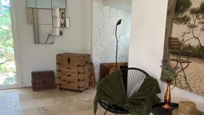 Tilava huone, jossa on suuri ikkuna, peilillä päällystetty seinä ja maalaishenkinen puinen arkku.