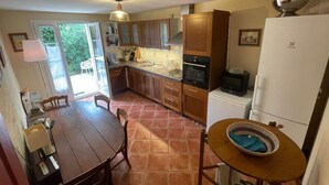 Una cocina compacta con armarios de madera, un refrigerador blanco, un microondas y una mesa de comedor con sillas.