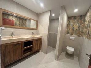 Een moderne badkamer met een houten wastafelmeubel, een grote spiegel en een douchecabine.