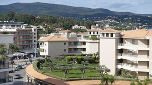 A residential area with apartment buildings, a curved road, and a mountain in the background. - Rare product (T3) in the heart of Cavalaire  (Cavalaire-Sur-Mer)