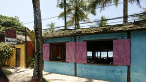 A building with pink shutters, a sign for 'Badave restaurant e bar', and a paved entrance. - Juquehy Condominium Oceanfront 42: best location on the beach  (Praia de Juqueí)