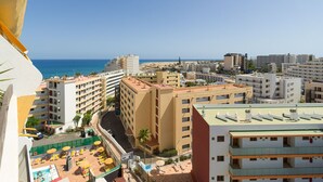 Eine Küstenstadt mit Blick auf das Meer, mit mehrstöckigen Gebäuden, einem Parkplatz und Außenbestuhlung.
