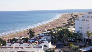 Blick auf die Küste mit Strand, Gebäuden und blauem Himmel.