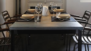 Une table à manger dressée avec des assiettes, des verres et une carafe, et une vue sur la montagne par la fenêtre.