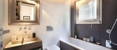 A modern bathroom with a vanity, toilet, and bathtub.