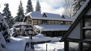 Eine schneebedeckte Lodge mit einem großen Hauptgebäude und einem kleineren Anbau links.