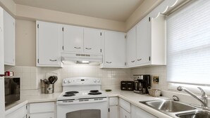 A kitchen with white cabinets, a stove, a sink, and a window with blinds. - Oneida St duplex 5 min walk to Lambeau 8 beds furnished full kitchen laundry (Green Bay)