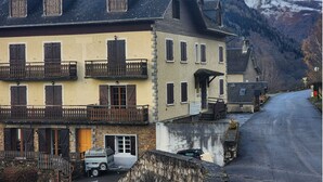 A traditional building with multiple balconies, a stone facade, and a view of snow-capped mountains in the background. - 68 m² *** self-contained apartment, large terrace, parking, surrounded by mountains. (Haute-Garonne)