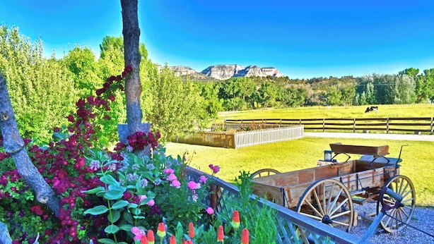A rustic outdoor setting with a wooden cart, a fenced area, and a mountain backdrop. - Cabin in Apple Orchard - Pool - Hot Tub -Farm -Breakfast -Quiet Side Zion -Bryce (Mount Carmel)