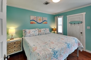 Une chambre à coucher avec un lit, deux tables de chevet, une porte et une fenêtre.