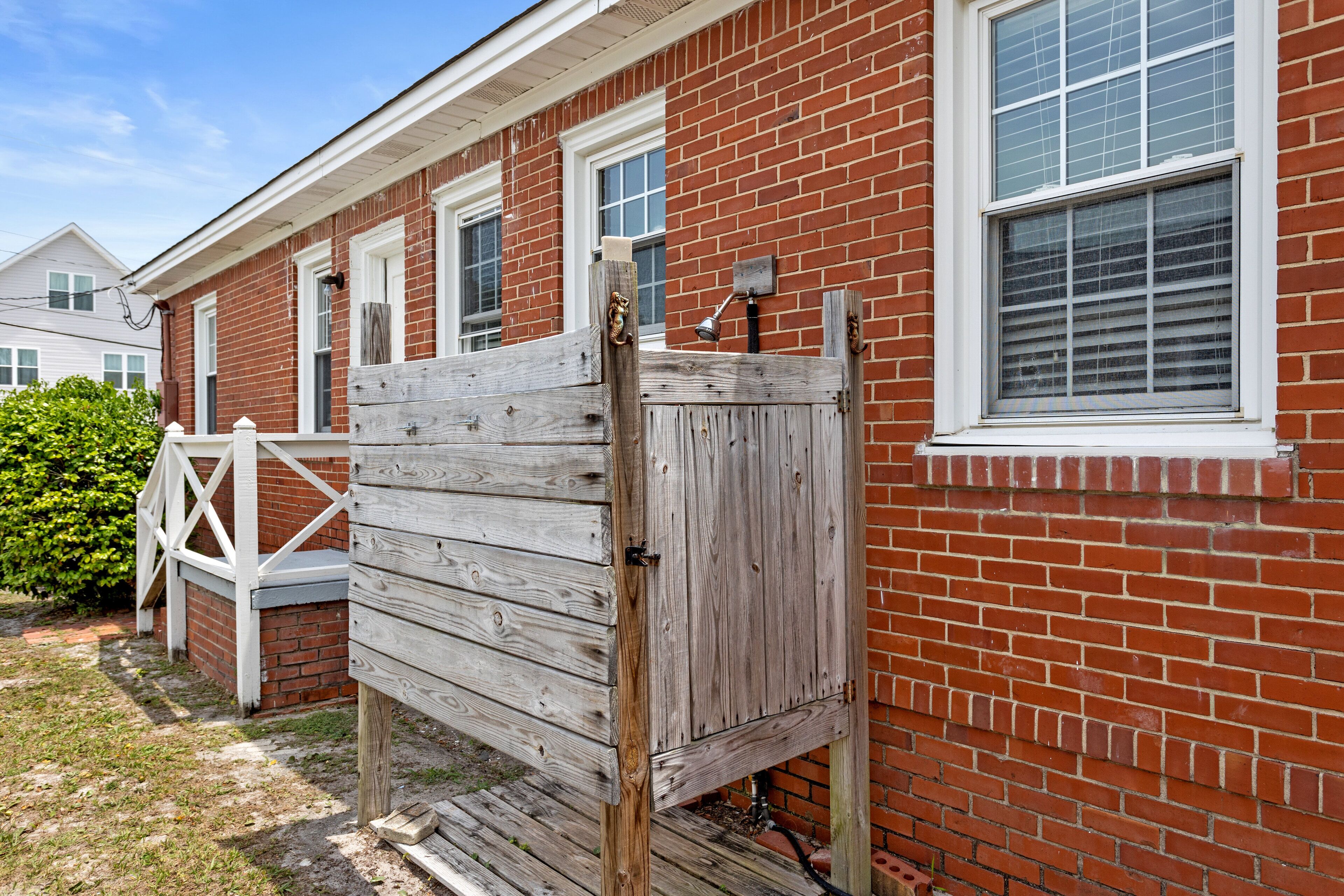 A red brick house with white-framed windows and a wooden gate.