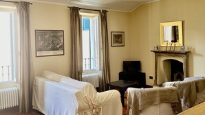 Una camera d'albergo con due letti, un camino, una televisione e opere d'arte alle pareti.