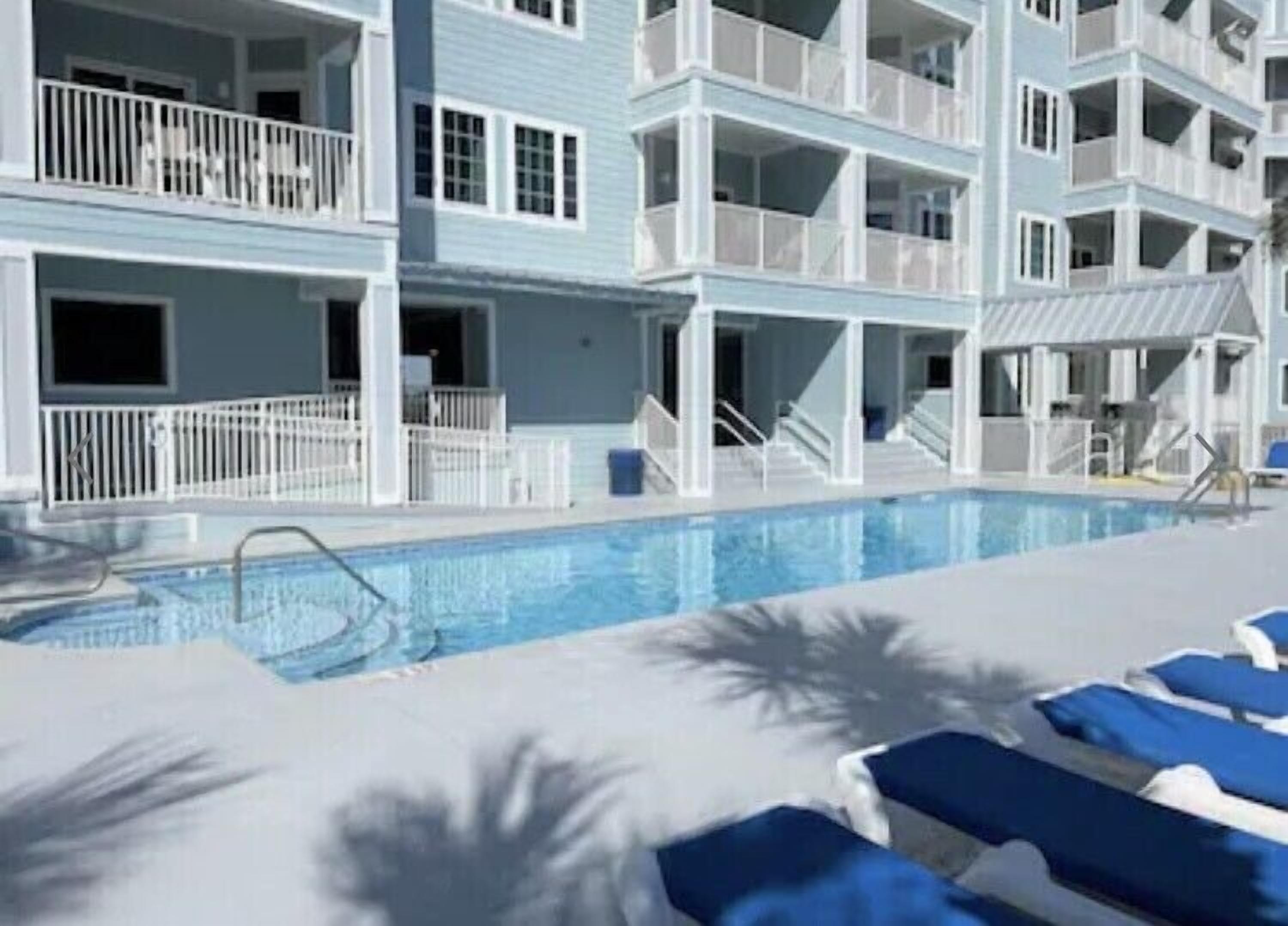A multi-story hotel with balconies, a swimming pool, and sun loungers.