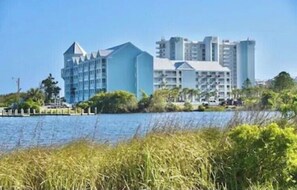 A coastal hotel with a modern design, featuring multiple floors and a prominent blue facade. - 423 Grand Caribbean Beach Condo - Amazing location with access to everything (Orange Beach)