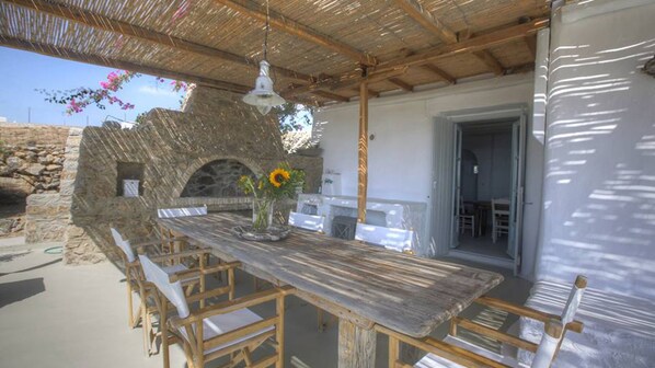 An outdoor dining area with a stone wall, wooden table, and chairs.