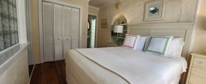 A bedroom with a bed, a nightstand, a dresser, and a door leading to another room.