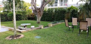 A well-maintained garden with a lawn, a tree, and outdoor furniture including a table and chairs.