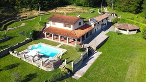 A large house with a swimming pool, a covered patio, and a stone wall surrounding the property. - Private pool, WIFI, walking distance facilities. Electric car charging point (Castiglione di Garfagnana)