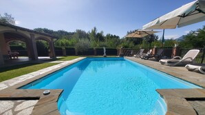 A rectangular swimming pool with stone edging, surrounded by a patio with lounge chairs and umbrellas. - Private pool, WIFI, walking distance facilities. Electric car charging point (Castiglione di Garfagnana)