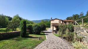 A stone pathway leading to a rustic house with a tiled roof, surrounded by greenery and a mountainous backdrop. - Private pool, WIFI, walking distance facilities. Electric car charging point (Castiglione di Garfagnana)