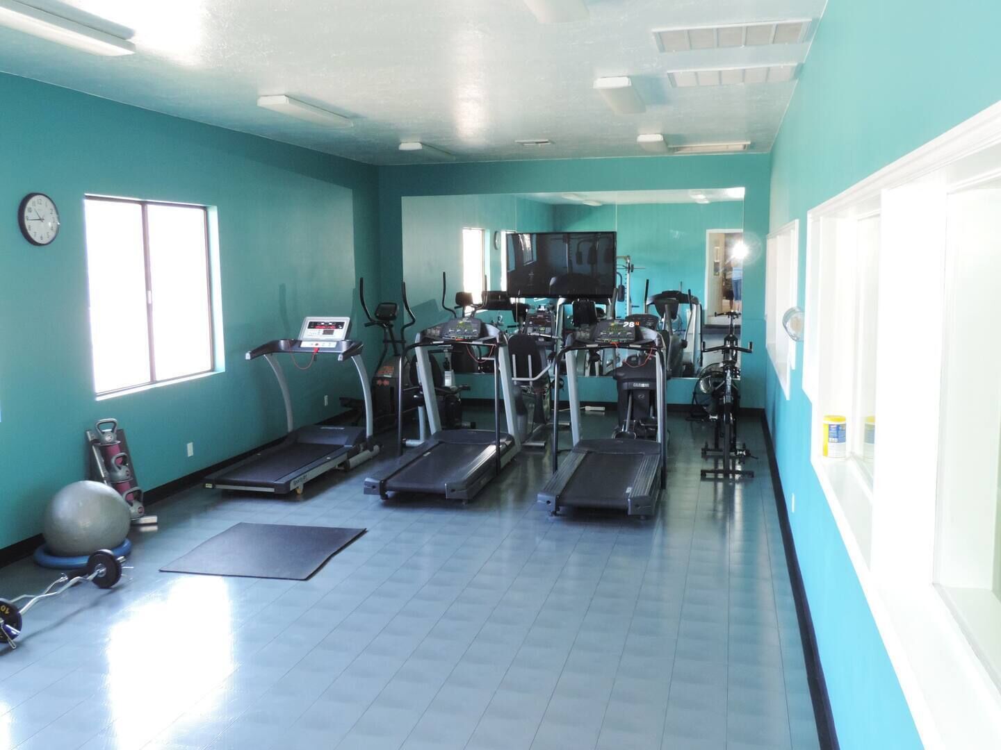 Un gimnasio con cintas de correr, elípticas y una bicicleta estática.