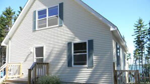 A two-story house with a front porch, a small garden, and a wooden fence. - Large Oceanfront house in Gouldsboro, Maine near Acadia NP; Views! (Gouldsboro)