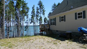 A house with a deck overlooking a lake, surrounded by tall trees. - Large Oceanfront house in Gouldsboro, Maine near Acadia NP; Views! (Gouldsboro)