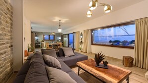 Un salon moderne avec un grand canapé d’angle gris, une table basse en bois et un coin repas à l’arrière-plan.