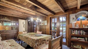Una habitación acogedora con paredes de madera, una mesa de comedor con mantel floral, una estantería y un candelabro.