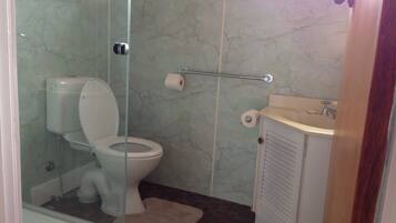 Une salle de bain comprenant des toilettes, une douche à parois de verre, un lavabo et un porte-serviettes.