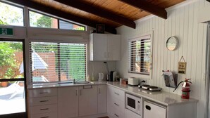 A kitchen with white cabinets, a microwave, a toaster, and a fire extinguisher. - Cranley Garden Retreat with Fireplace & Pool (Cranley)