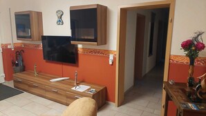 A modern living room with a flat-screen TV, wooden furniture, and a decorative vase. - 80 m², family-friendly, barrier-free apartment, overlooking the golf course (Sundern (Sauerland))