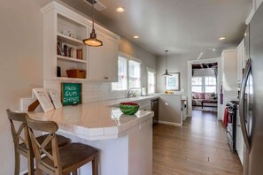A kitchen with a central island, white cabinetry, and a dining area with chairs.