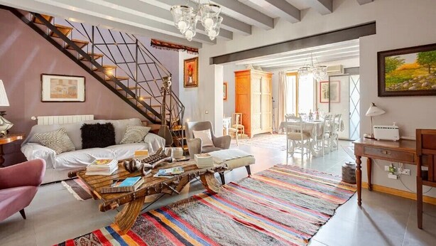 Un salón espacioso con una escalera, una mesa de centro, un sofá y una zona de comedor.