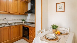 Une cuisine dotée de meubles en bois, d’un lave-vaisselle et d’un coin repas avec une table dressée pour deux personnes.