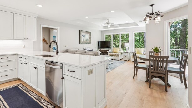 A spacious kitchen with white cabinetry, a central island, and a dining area with a table and chairs.