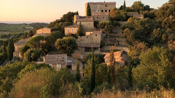 A historic stone building with multiple levels and a prominent tower, surrounded by lush greenery and trees. - Holiday home for 8 people (Vénéjan)