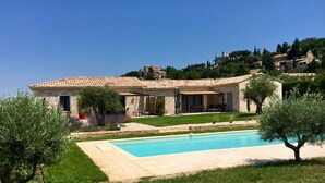 A stone villa with a swimming pool, surrounded by greenery and a clear blue sky. - Holiday home for 8 people (Vénéjan)