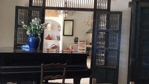 Un comedor con un piano, una silla de madera y una mesa.