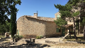 Un edificio de piedra con tejado de baldosas, rodeado de árboles y un camino de piedra.