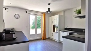 Una cocina moderna con armarios blancos, encimera negra y horno integrado.